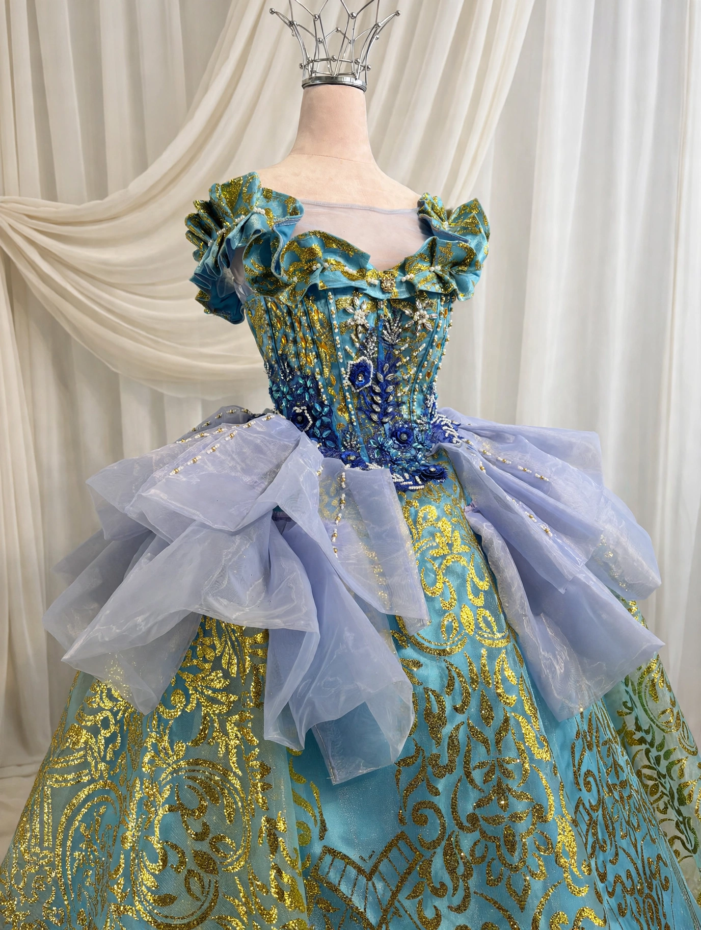 Close-up of gold baroque embroidery and beaded bodice with blue floral appliques